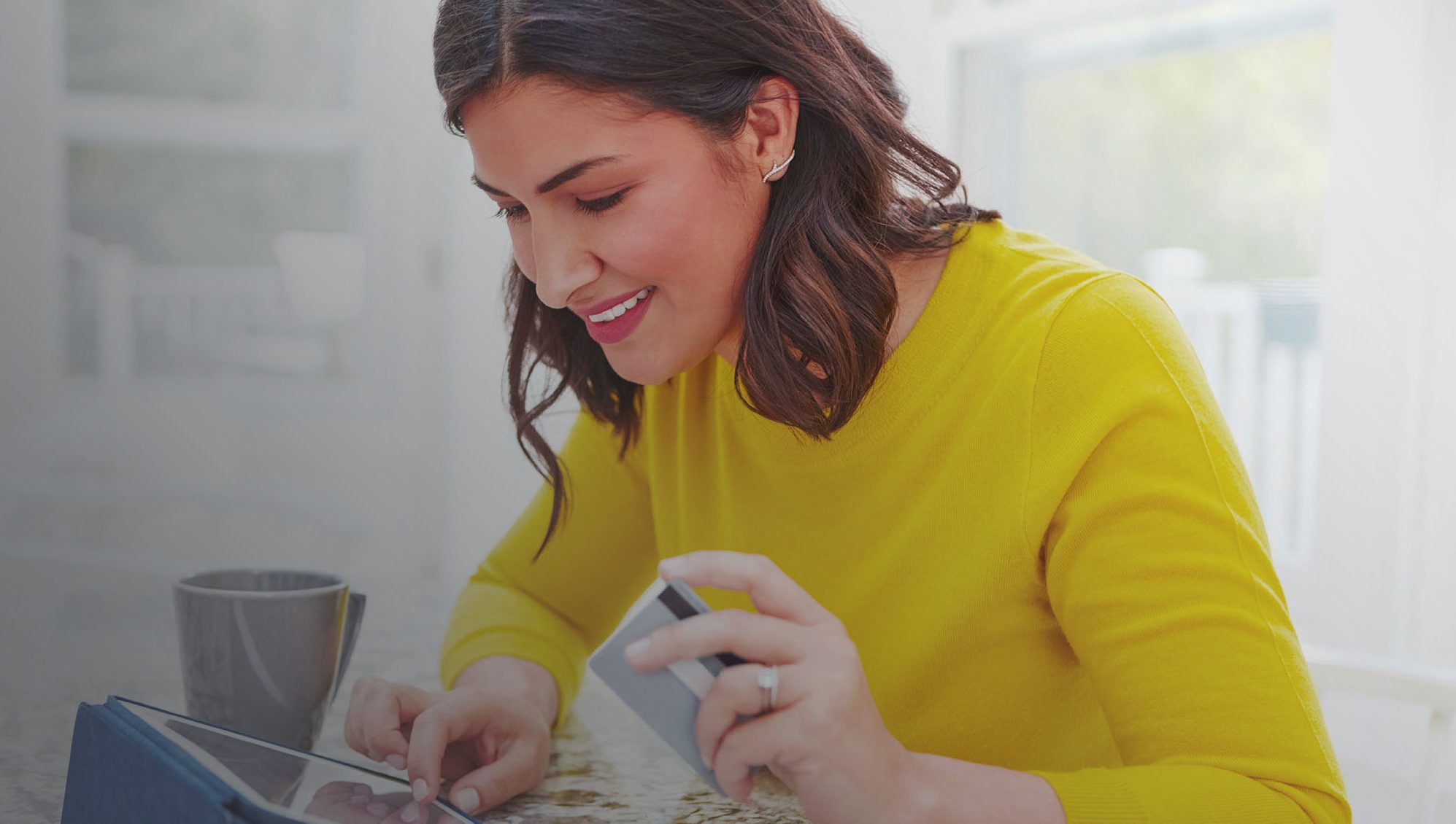 Shot of a woman using her tablet and credit card at home